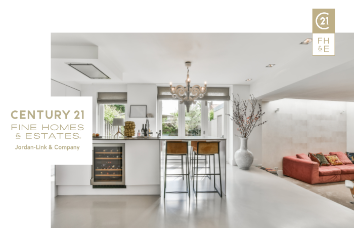 Elegant open-plan kitchen with modern design, white countertops, and bar stools, featuring Century 21 Fine Homes & Estates logo