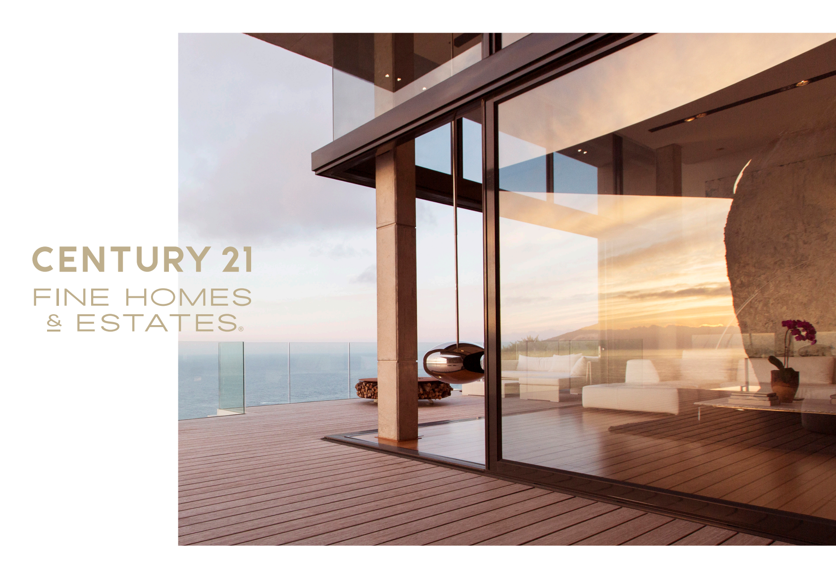 Luxury home with glass facade and sea view at sunset, featuring CENTURY 21 Fine Homes & Estates branding